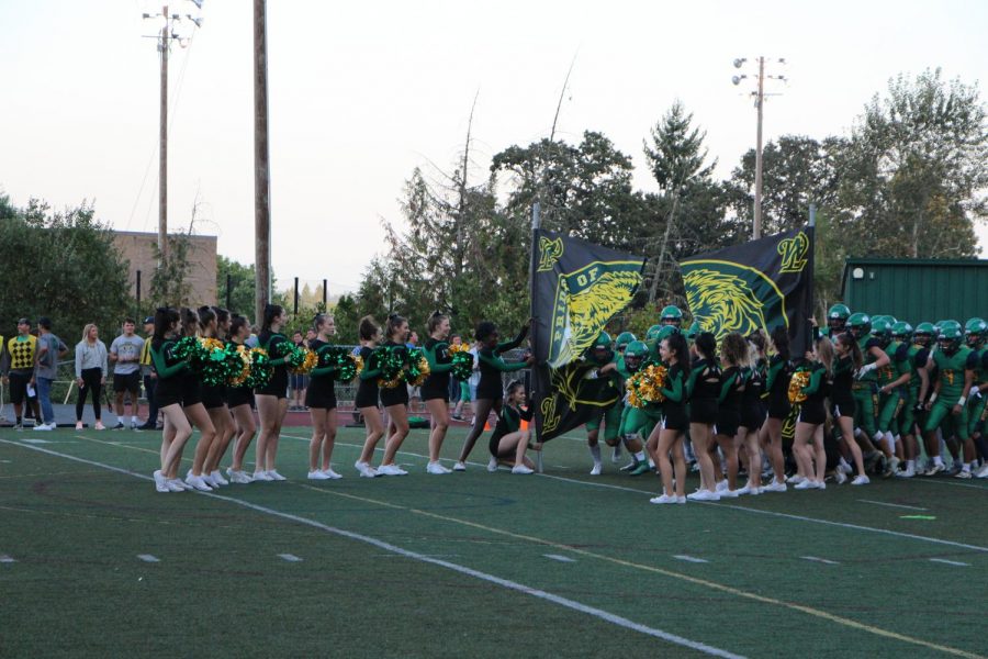 Players break through the  West Linn banner to start the game.