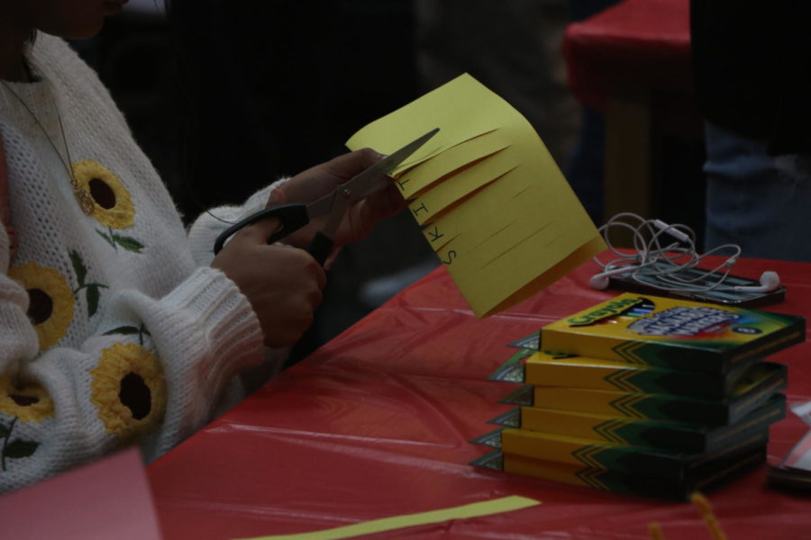 A student cuts paper to create a lantern. This station focused on cutting paper and folding them to create lanterns which are a huge theme of the Lunar New Year. It also provided markers, pens, and pencils to write your aspirations on them.