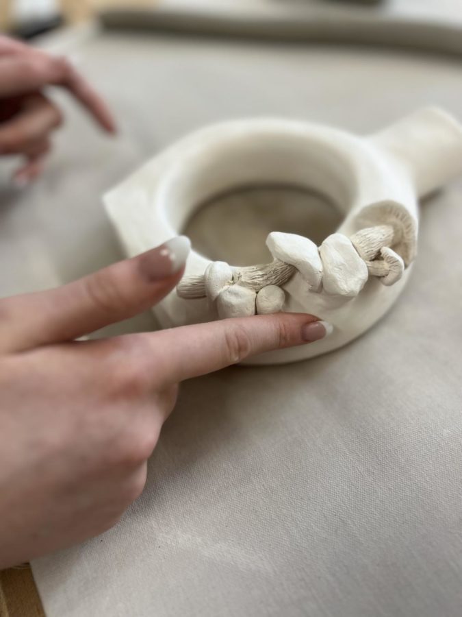 On her most recent artwork, Baker runs her finger over the pieces checking for imperfections and sharp pieces of ceramic that may be hidden from the eye. “I especially need to watch out for the mushrooms, the texture of the stipe could have a lot of sharp pieces that I may need to sand down,” Baker says while continuing to fine-tune her piece. 