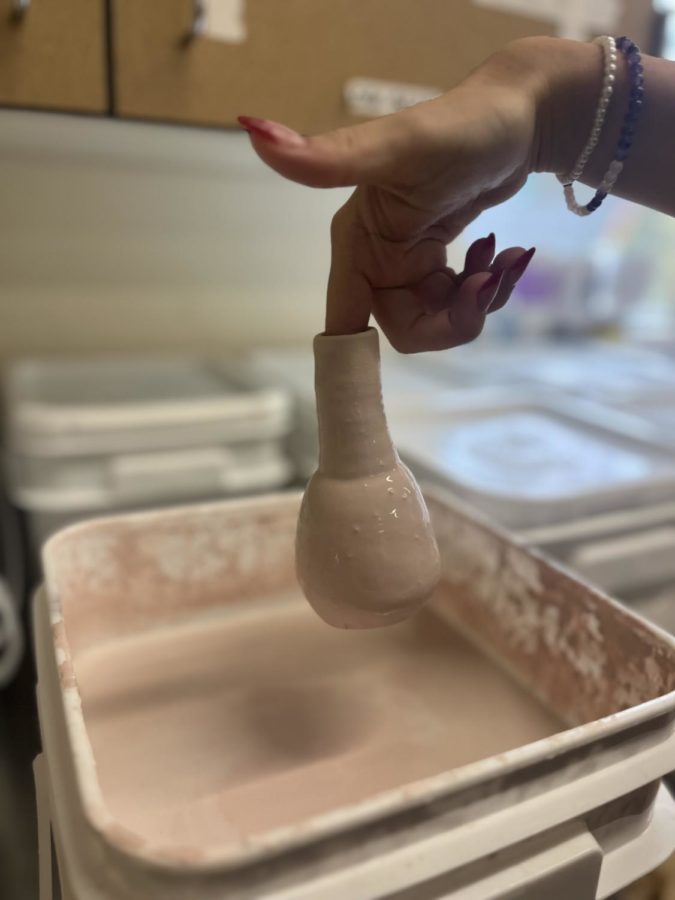 Taking a different approach to glazing, Alexis Corso, senior, utilizes the stem of her mini vase to get an even dip. 