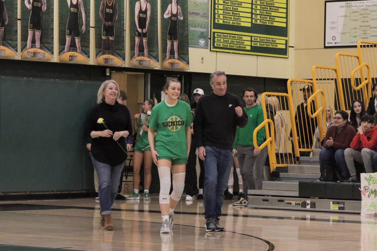 Alaina Moore, senior, walks on to the court with family to join the ceremony. Moore has been on the varsity team for three years. “I’ve learned a lot about leadership, and especially just being there for those that you care about,” Moore said.