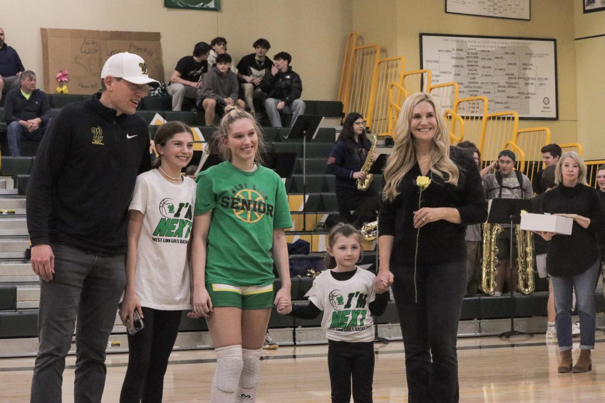Maci Churchill, senior, poses with family on the court once it was her turn during the ceremony. Younger family members wear shirts that read, “I’m next” in support of the West Linn womens basketball program.