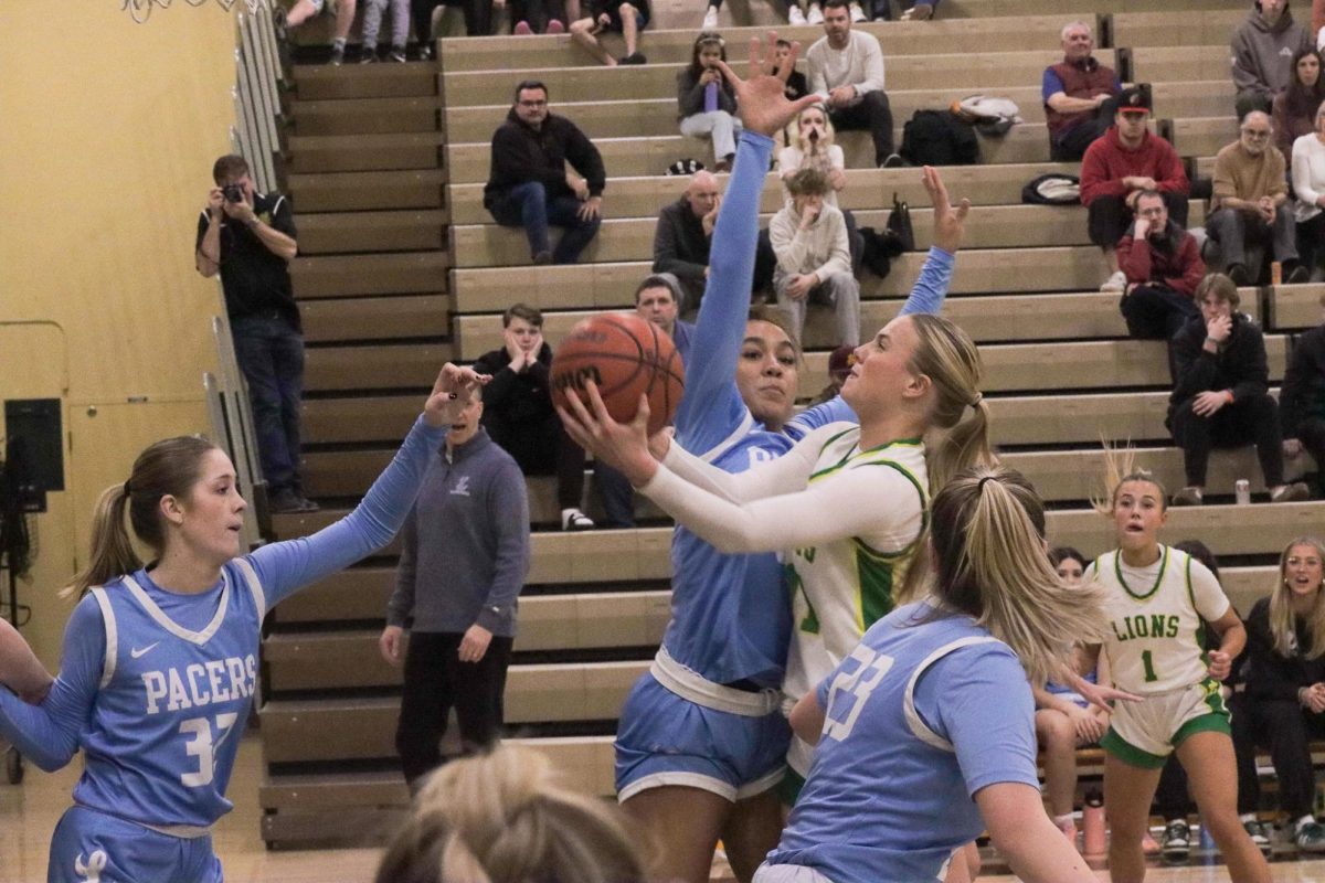 Surrounded on all sides. Reese Jordan, sophomore, goes for the shot while being guarded by Lakeridge Pacers players.