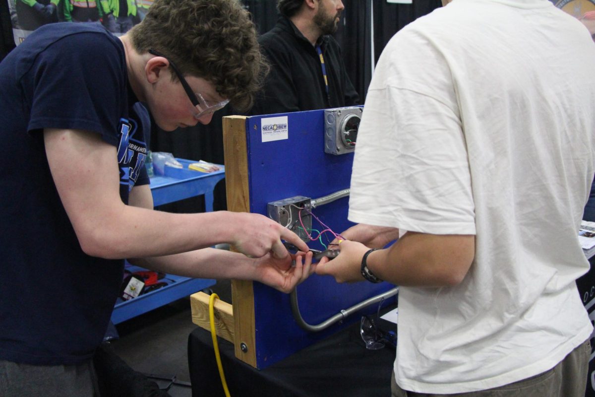 Participants in Youth Career Fair rearrange wires in a test outlet at the NECA-IBEW Electrical Training Center booth.
