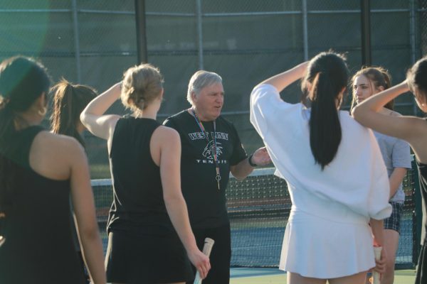 Rally up. Robert Shevlin, the womens tennis team coach, gathers the varsity and junior varsity players together to prepare for their first match of the season on March 13 against Lakeridge.