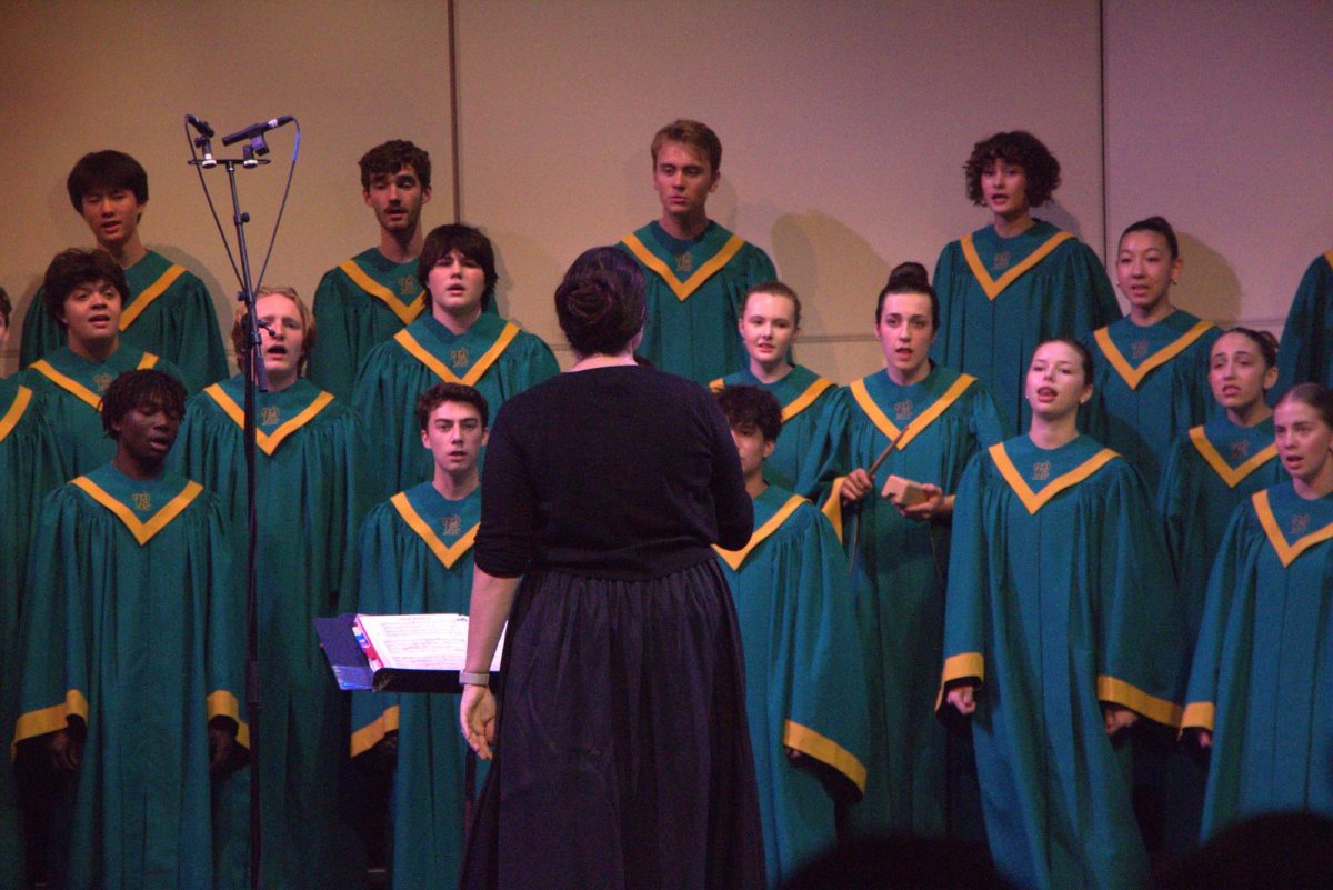 Singing to the beat. Annie Kubitschek, choir teacher, directs the symphonic choir while Shannon Wianko, junior, plays percussion for the song “Muie Rendera.” On Oct. 21, all five of West Linn’s choir classes performed their first concert in the Performing Arts Center (PAC). One of the choirs was Symphonic Choir which was the last group to perform. Brody Olson, junior, sings Bass 2 in both Symphonic Choir and Fresh Pitch. “A lot of practice, tracks and sectionals [went into preparing],” Olson said. “There's a lot of discipline. Just constantly repeating, memorizing, [and] learning.”