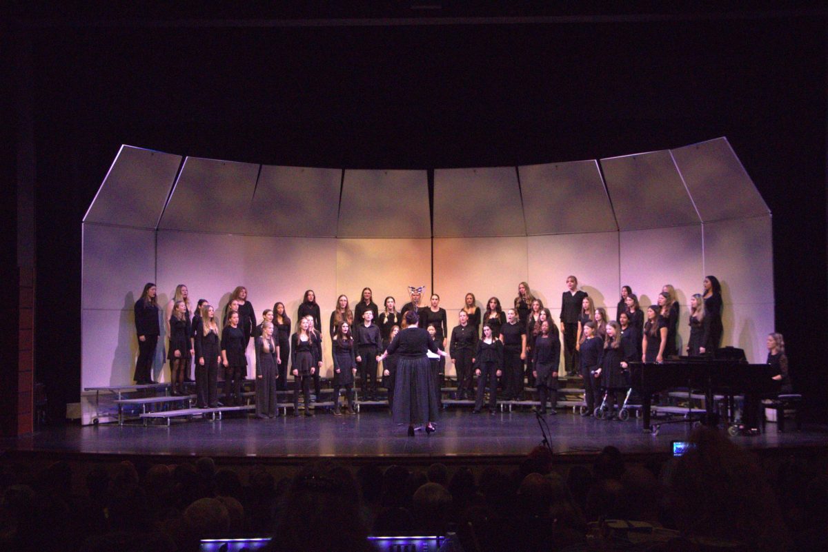 The Bella Forte choir sings while Kubitschek conducts and Naomi LaViolette plays piano accompaniment. 