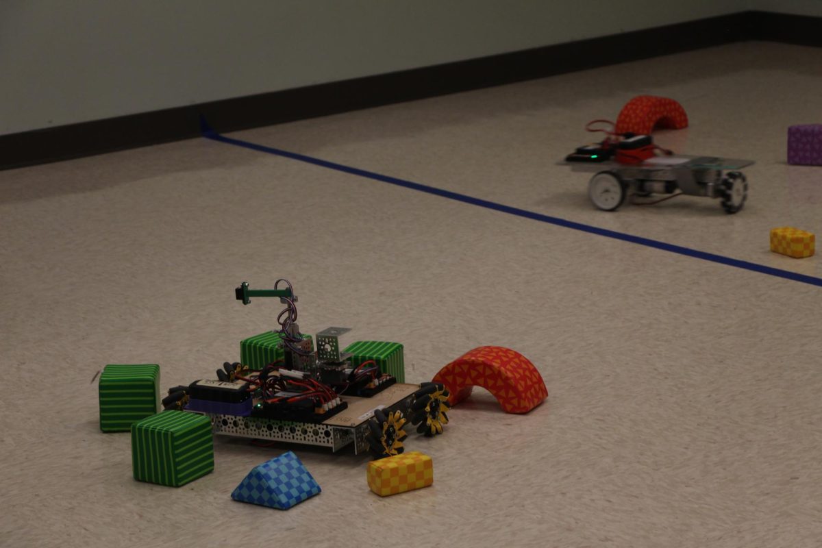 In between the lines. Blue tape splits the room  into four sections for four different students to try driving the robots in their respective spots. The event took place in The Hollow, a part of the children’s section in the library.