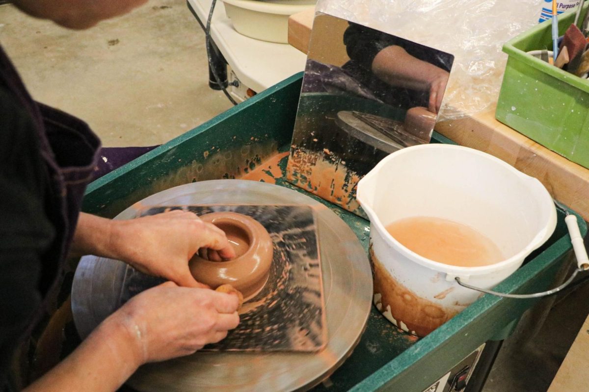 Going for a spin. Garvey creates a bowl and shows the different dynamics students can use when spinning the wheel. This is one of the ways Garvey instructs ceramic students on how to make their pieces. The mirror is used to see the clay from the opposite angle. 