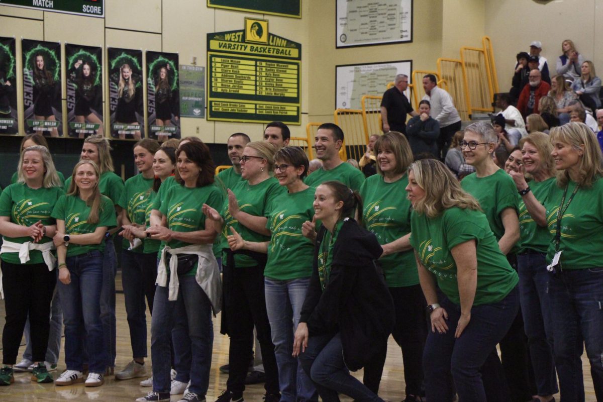 Green all together. Teachers pose in the center of the main gym after hearing Brigham Baker’s speech for the first time that night, all wearing the ‘You Make A Difference’ shirt gifted to them by a student from either the mens or womens teams.