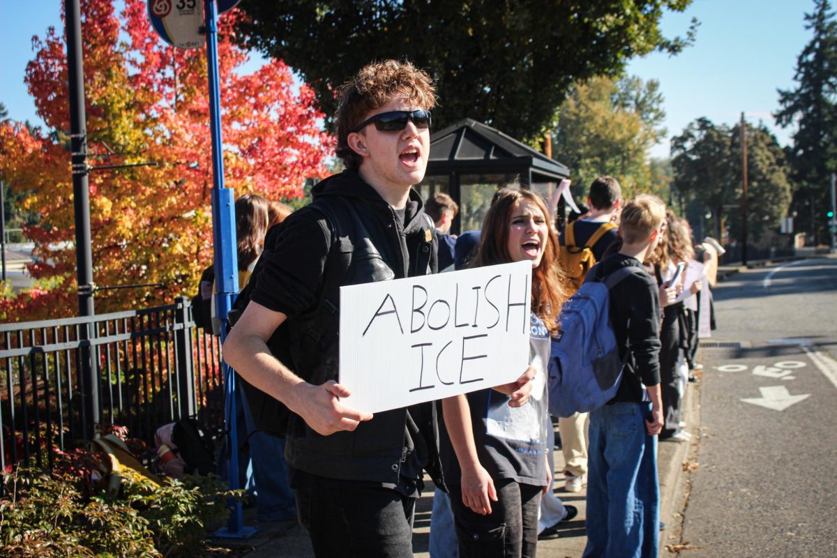 Gabe Garrett, senior, participates in anti-ICE chants while holding a sign that says "abolish ICE."